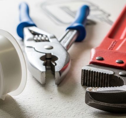A complete plumbing equipment checklist laid out on a wooden workbench, including wrenches, plungers, and pipe tape