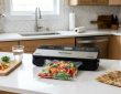 Budget vacuum sealer machine packaging fresh vegetables on a kitchen counter.