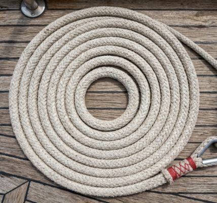 Sailor tying a secure knot in a white anchor rope.